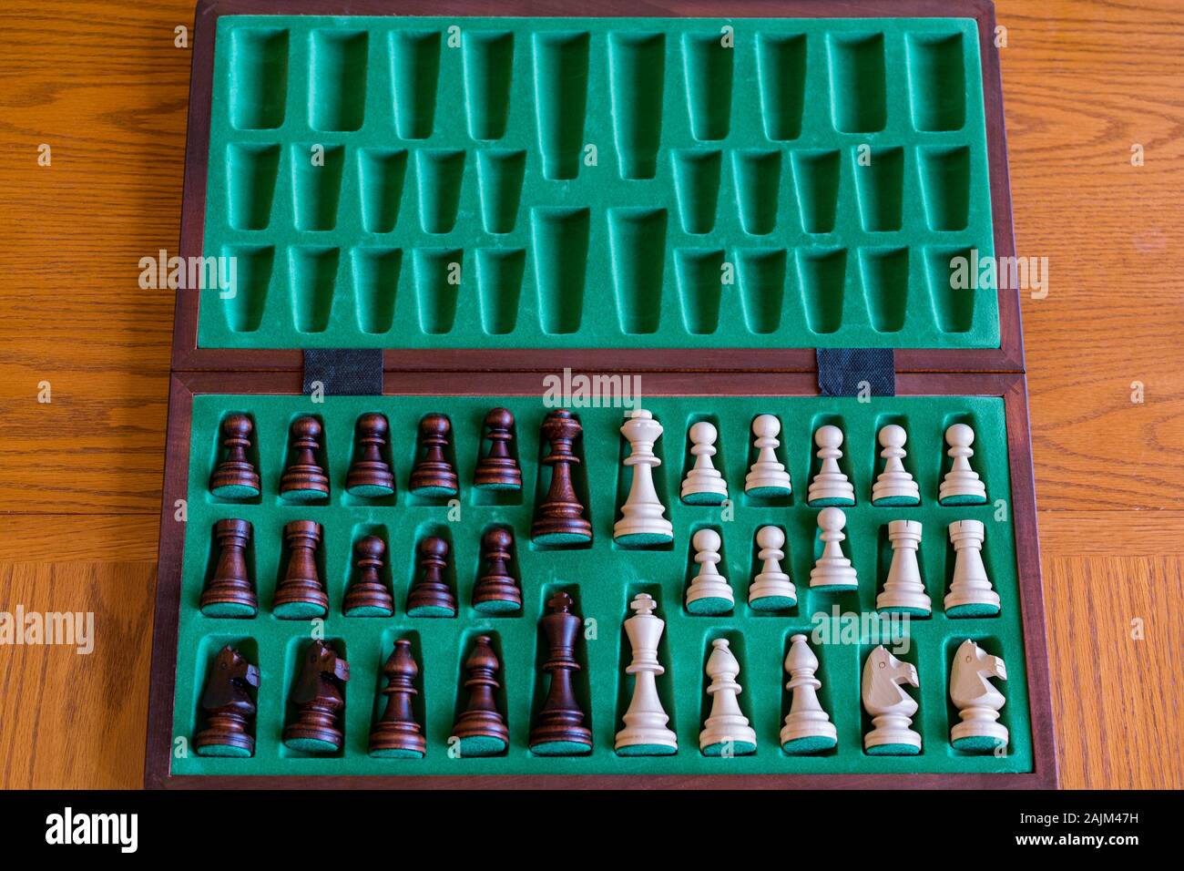 A wooden chess set in its box, view from above with brown background. The picture shows old traditional hand-made chess in a box. Stock Photo