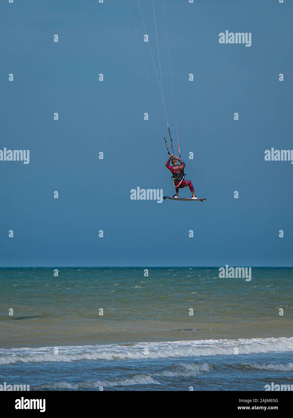 Kite Surfer from behind jumping up high in the sky Stock Photo