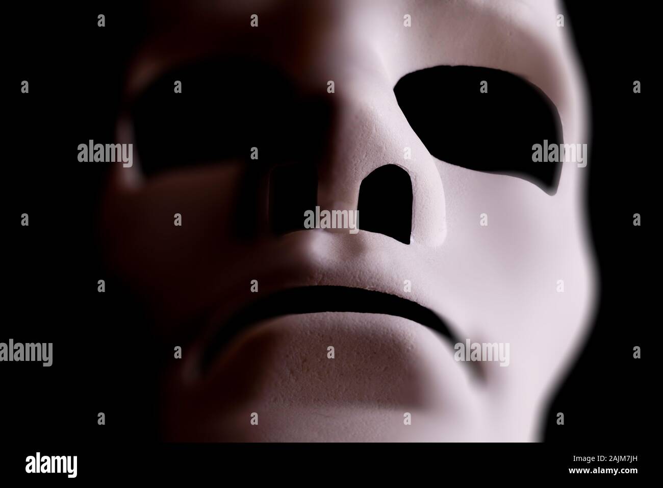 Blank mask close up in the shape of a human face, with black background. Stock Photo