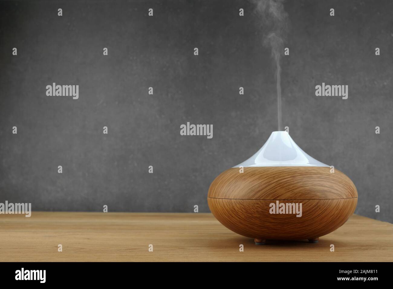 Aroma oil diffuser on wooden table and grey background Stock Photo
