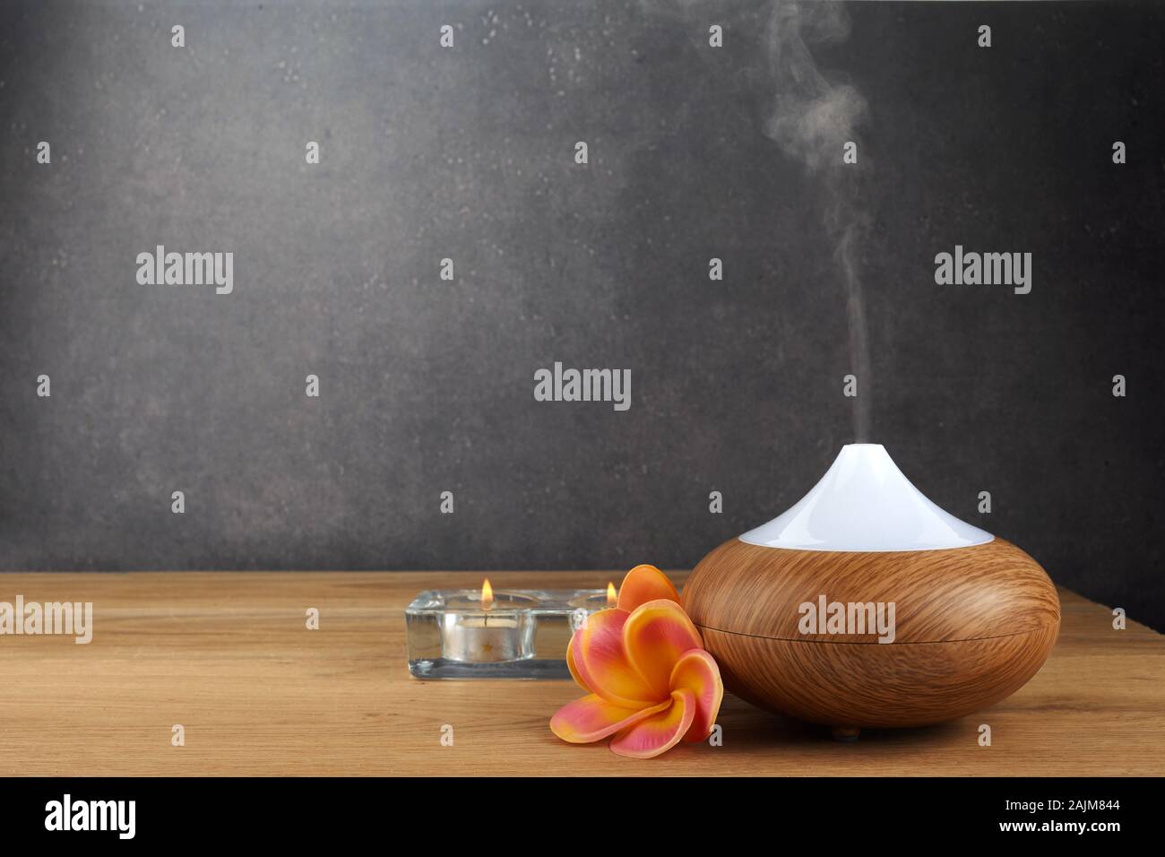 Aroma oil diffuser, candles and flowers on wooden table Stock Photo