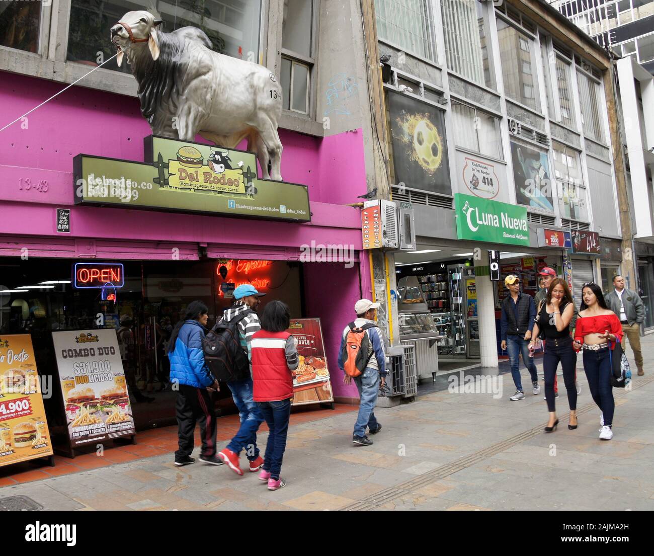 People walking past Del Rodeo restaurant and stores along Carrera 7 in La Candelaria district of Bogota, Colombia Stock Photo