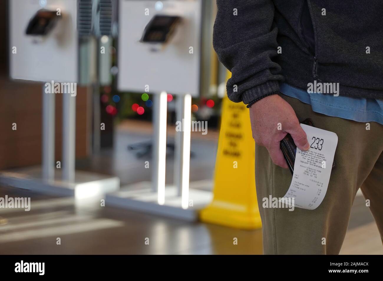 Cromwell, CT / USA - November 25, 2019: Asian man waiting in line holding his receipt with his order number Stock Photo