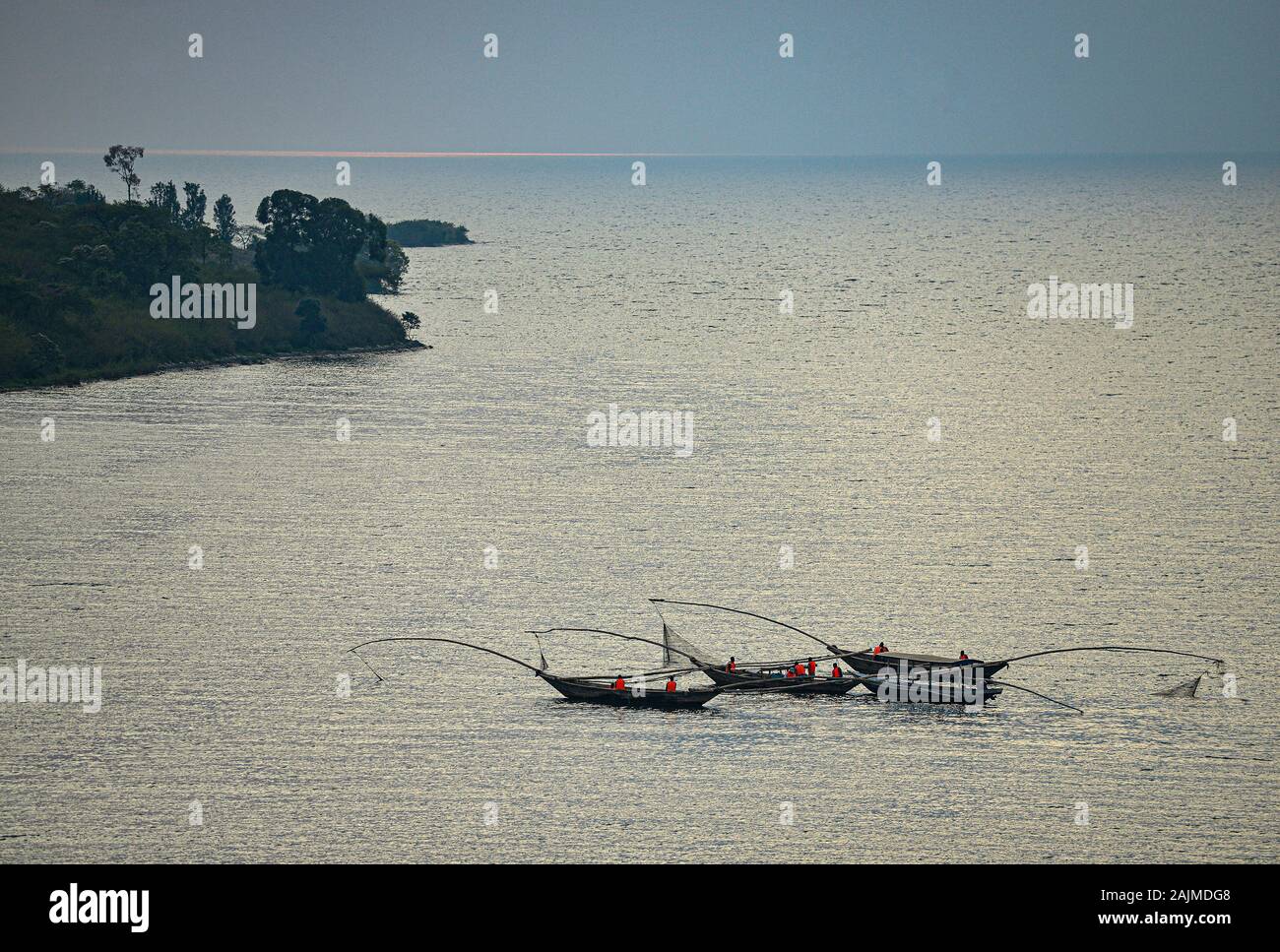 Fishing Canoes on the Lake with the Sun's Reflection on Water. Lake Kivu, Rwanda. Lake Kivu is shared by Rwanda and the Democratic Republic of Congo. Stock Photo