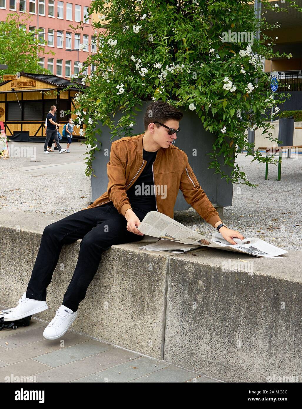 Male fashion model takes a break from photo shoot to read the newspaper, lookiing ultra cool in the process.  Germany. Stock Photo