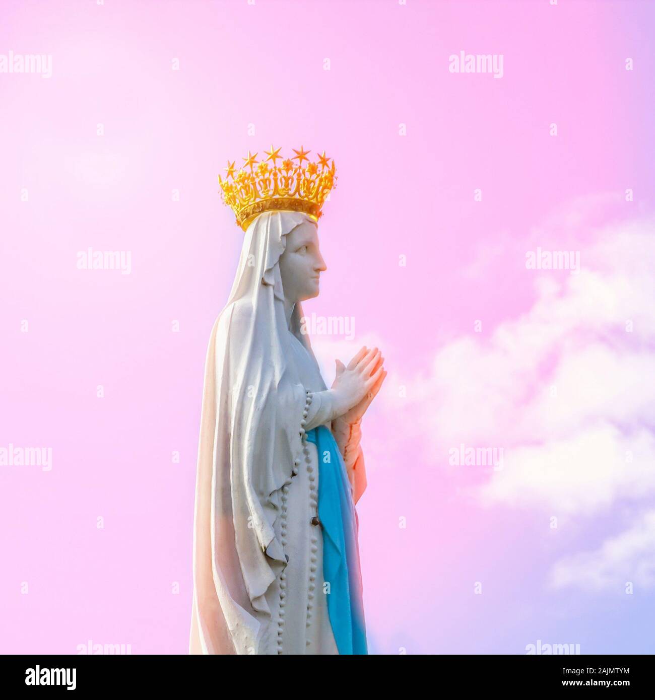 Virgin Mary statue on the pink sky background. Statue of Our Lady