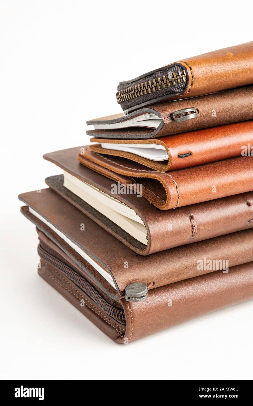 A stack of leather-bound journals, notebooks, cases, and wallets set on ...