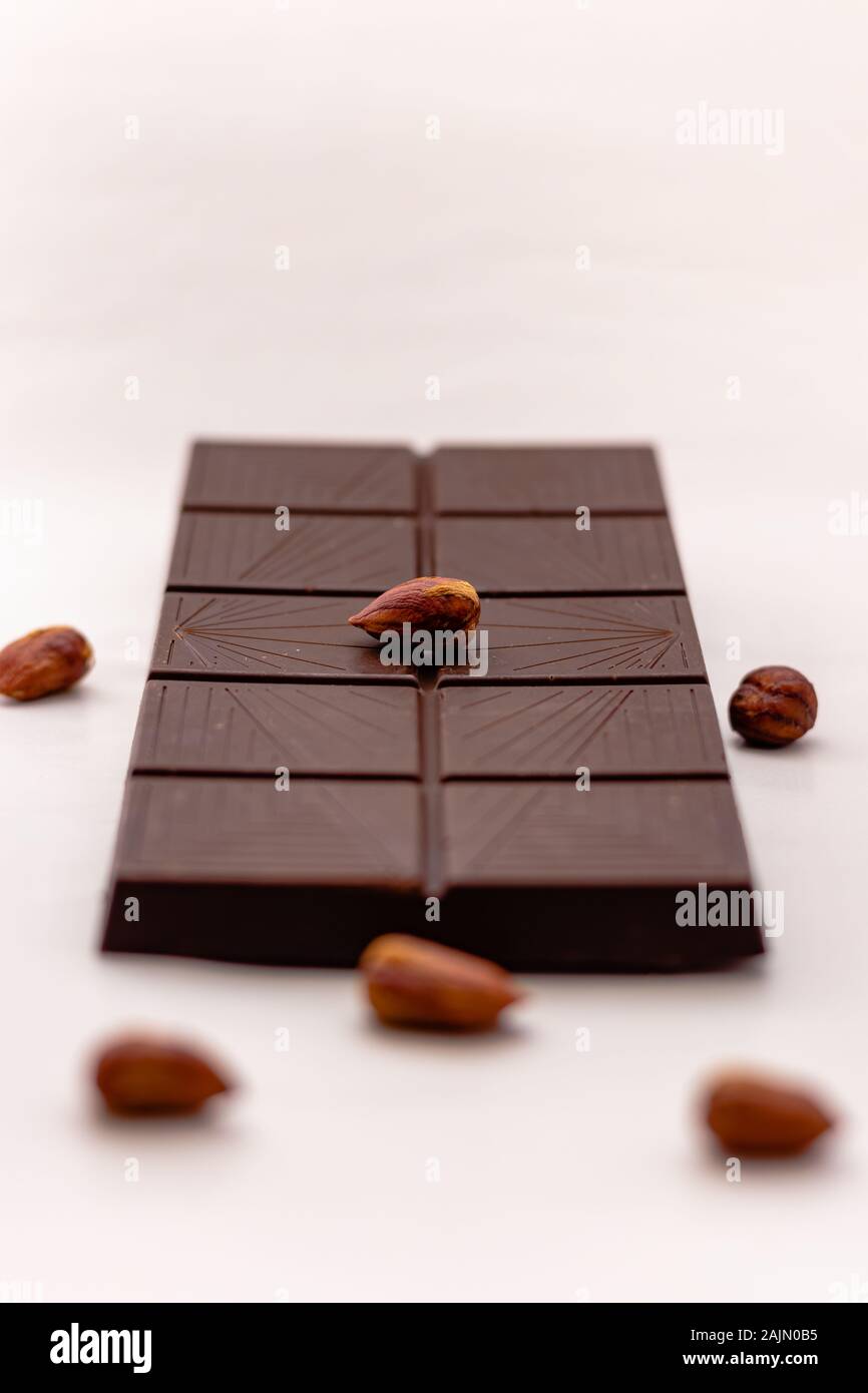 Dark chocolate with whole hazelnuts isolated on white background Stock Photo