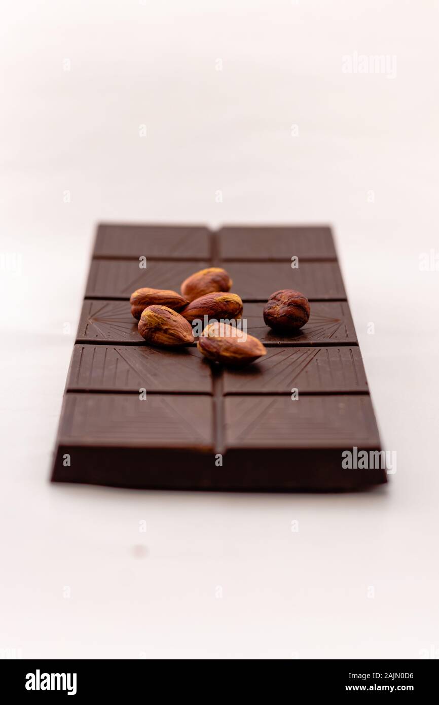 Dark chocolate with whole hazelnuts isolated on white background Stock Photo