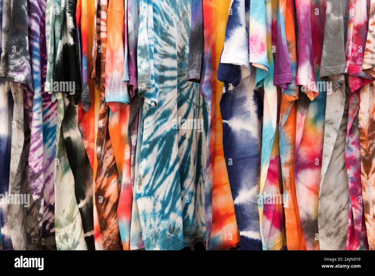 Colourful tie dye shirts hanging on a clothes rail at the hippy market in the town of Es Canar, Ibiza, Balearic Islands Stock Photo