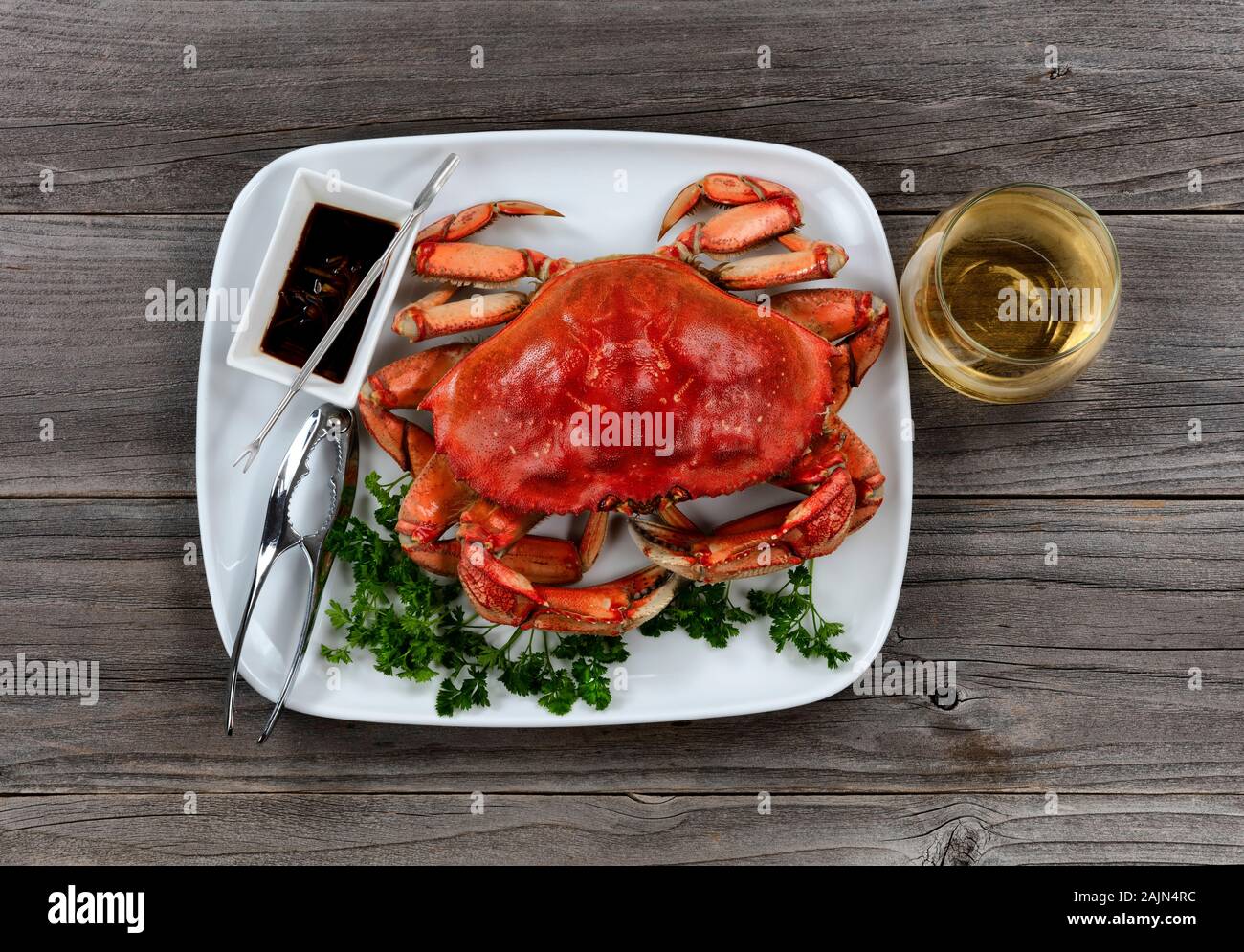 Whole Dungeness crab in dinner setting with wine on wooden table in top