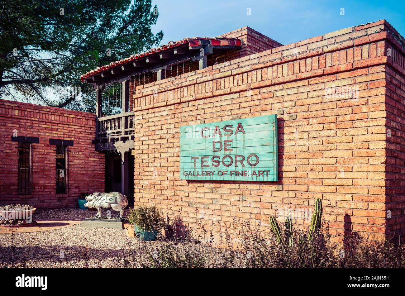 Southwestern adobe brick building houses Casa de Tesoro, Gallery of fine Art, with Javalina sculpture at entrance and turquoise sign at sunset Stock Photo