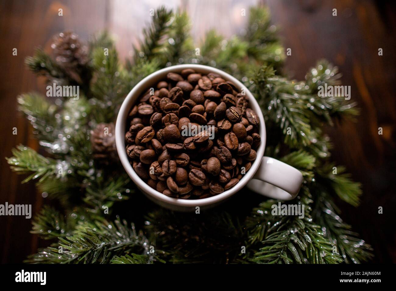 High side angle shot of coffee beans in white coffee cup winter greens Stock Photo