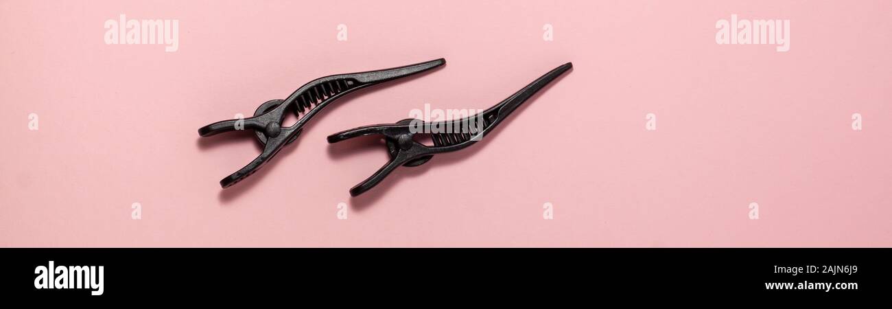 Banner flat lay of professional hair clip on pink background flat lay top view. Hairdresser salon equipment concept with copy space Stock Photo