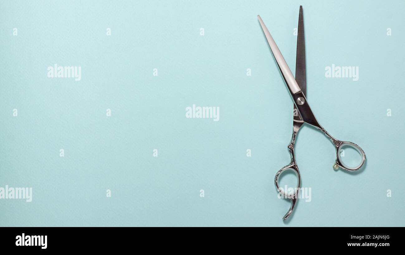Flat lay of professional hair cutting shears on the right side on blue background. Hairdresser salon equipment concept with copy space Stock Photo