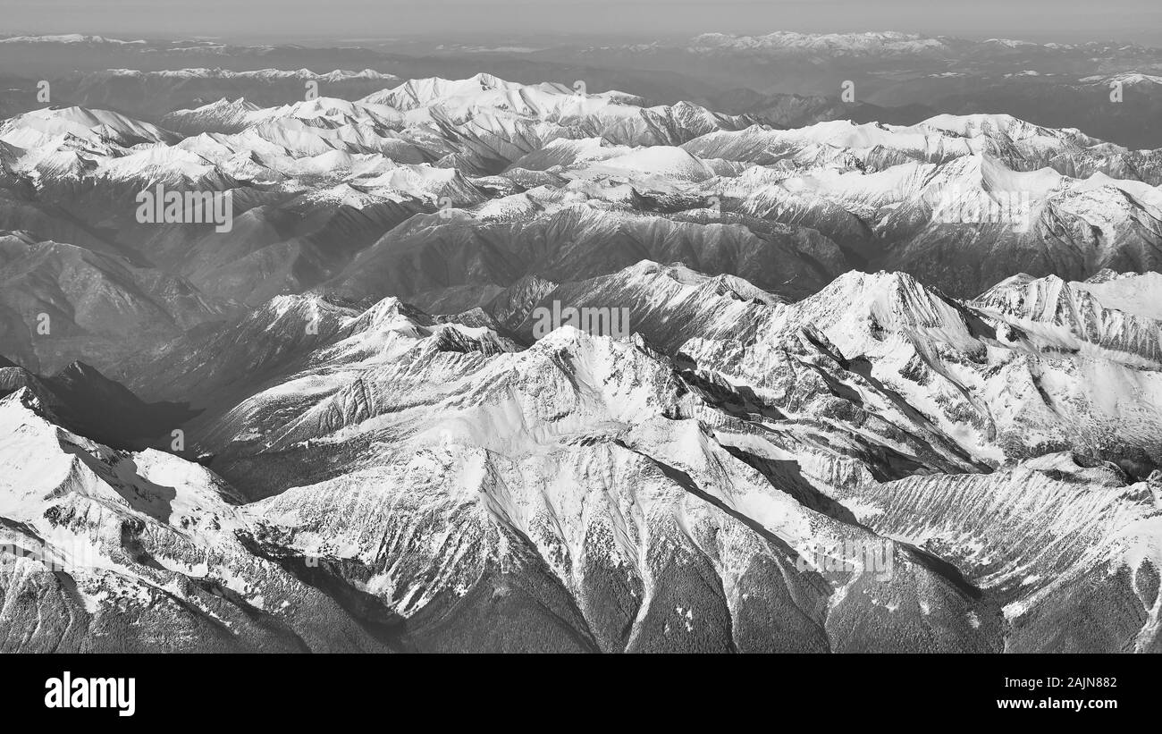 A black and white view of the snow covered rocky mountains over British Columbia viewed from a commercial plane. Stock Photo