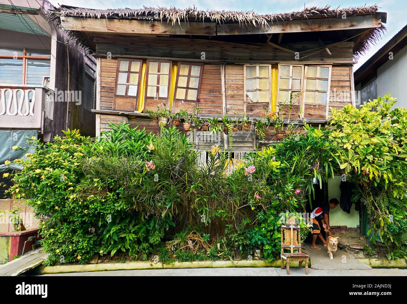 Romblon Town, Philippines: Old, broken traditional wooden building surrounded by plenty of plants and flowers in front Stock Photo