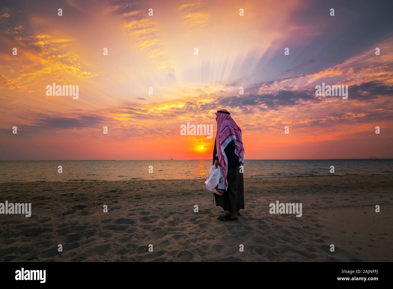 An arab old man standing in Fanateer beach with sunrise background. Al Jubail City -Saudi Arabia. Stock Photo