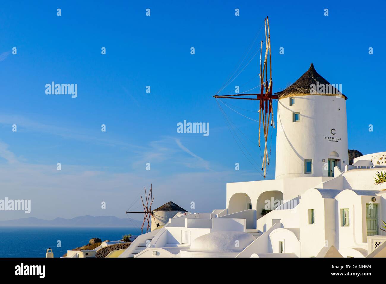 Windmill and traditional white buildings facing Aegean Sea in Oia, Santorini, Greece Stock Photo