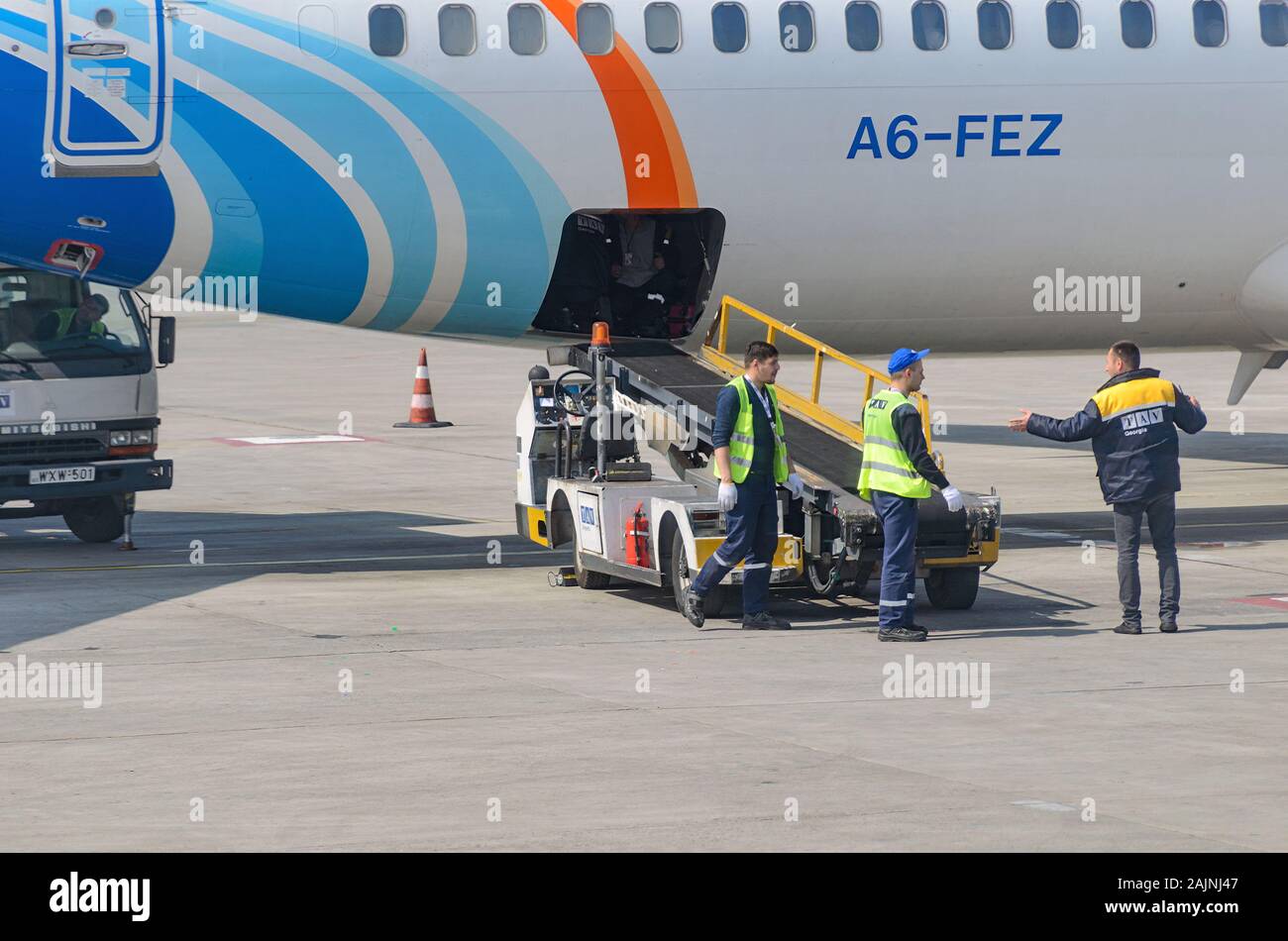 Airport ground staff near the conveyor belt for luggage at the plane. Georgia, Tbilisi, 2019-04-10 Stock Photo