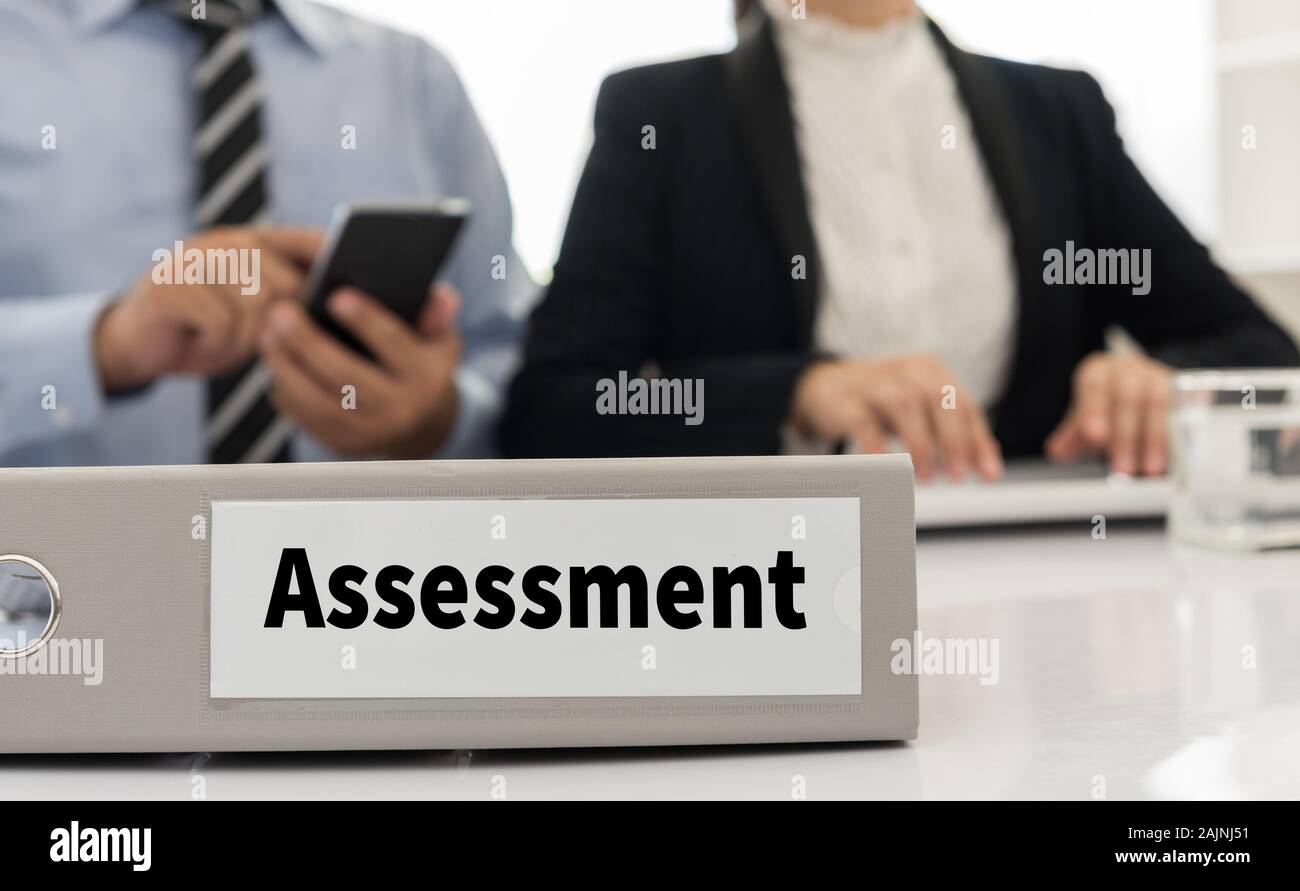 assessment file on desk with executives and auditors in office Stock