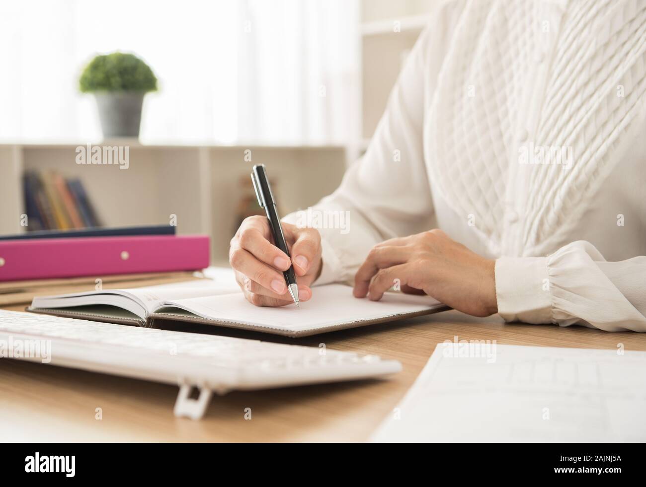 working woman write down appointments or notes meeting schedule for planning works in her office Stock Photo