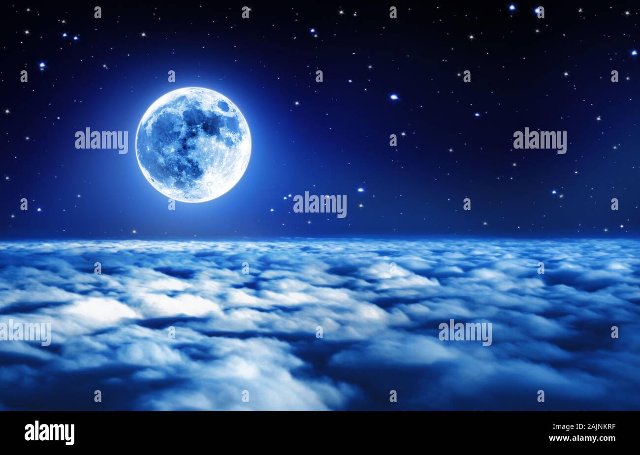 Bright full moon in a starry night sky above dreamy clouds with soft glowing light Stock Photo