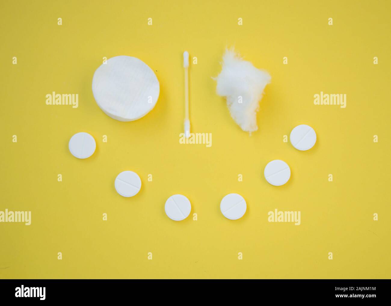 Clean white cotton pads, ear stick and pills that forms smiley face, healthcare concept, yellow background Stock Photo