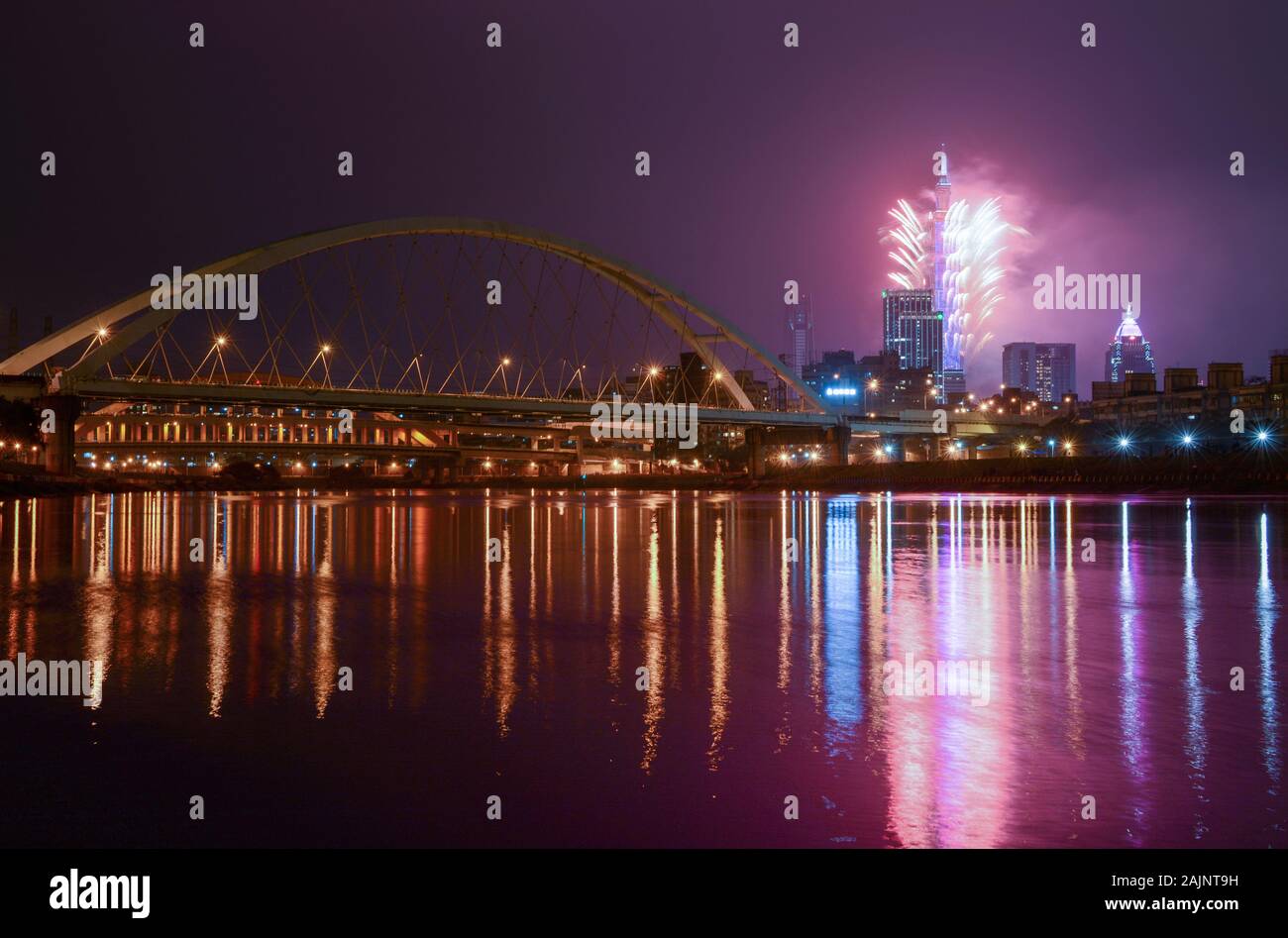New Year fireworks light up the Taipei City skyline, casting reflections in the Keelung River Stock Photo