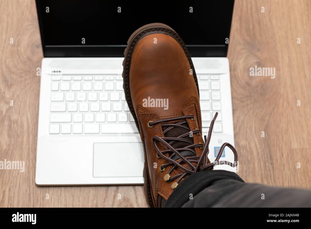 Frustrated man kicking a laptop with brown boots on office floor Stock ...