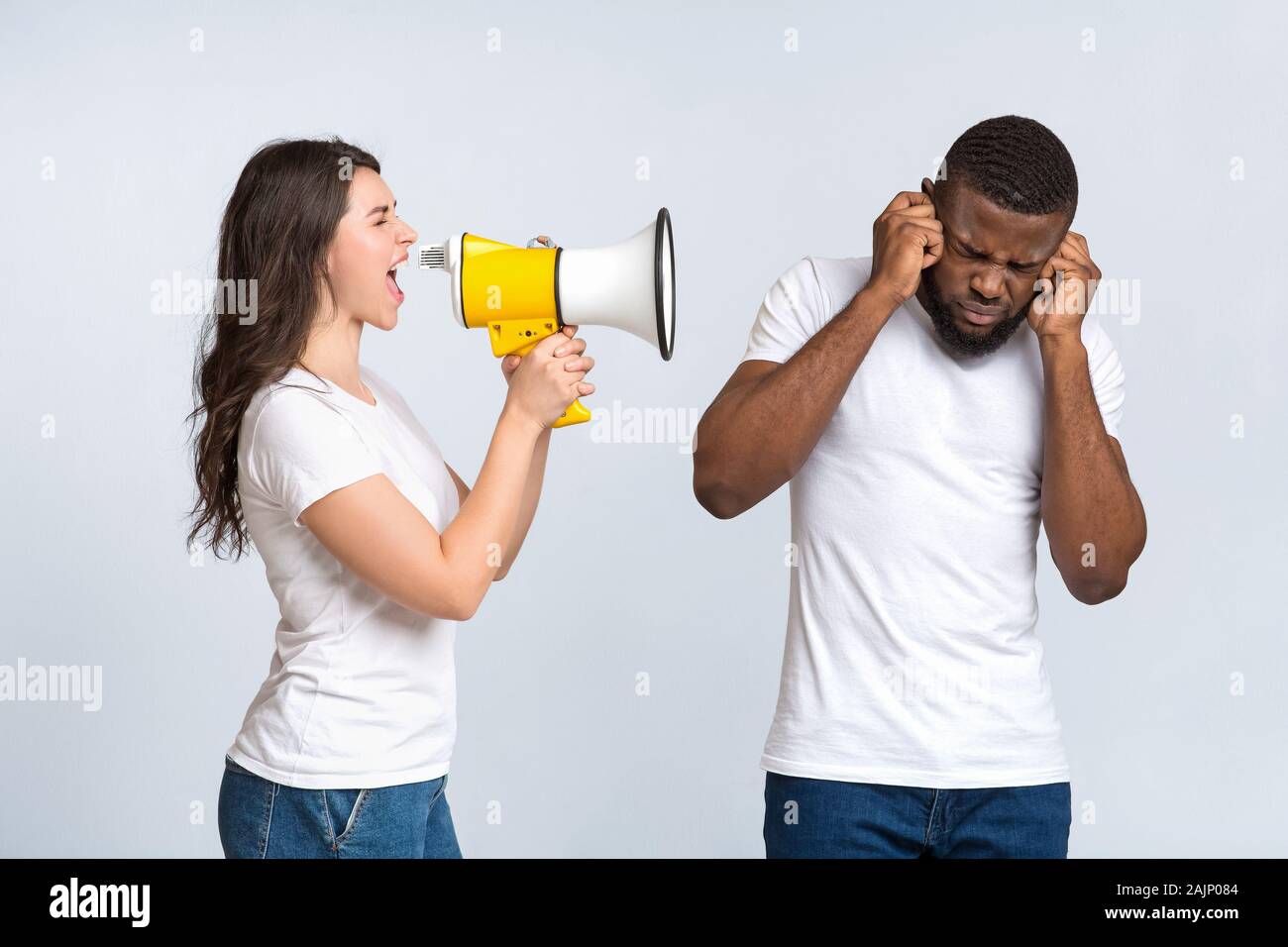Irritated young woman screaming with megaphone at her man, that closing