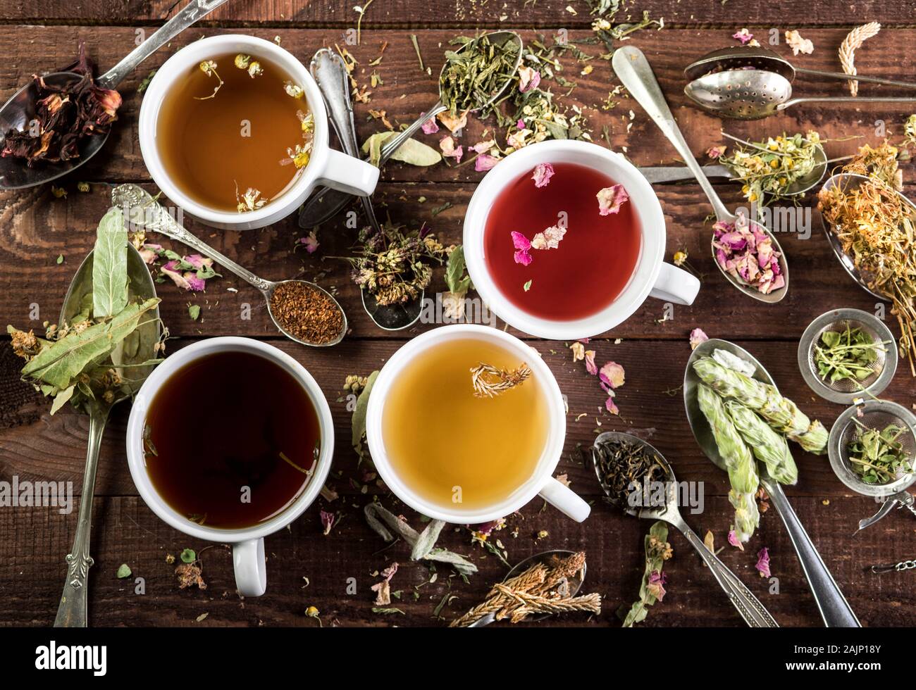 Assortment of cups of tee and dry tea in spoons a on wooden background. Top view. Stock Photo