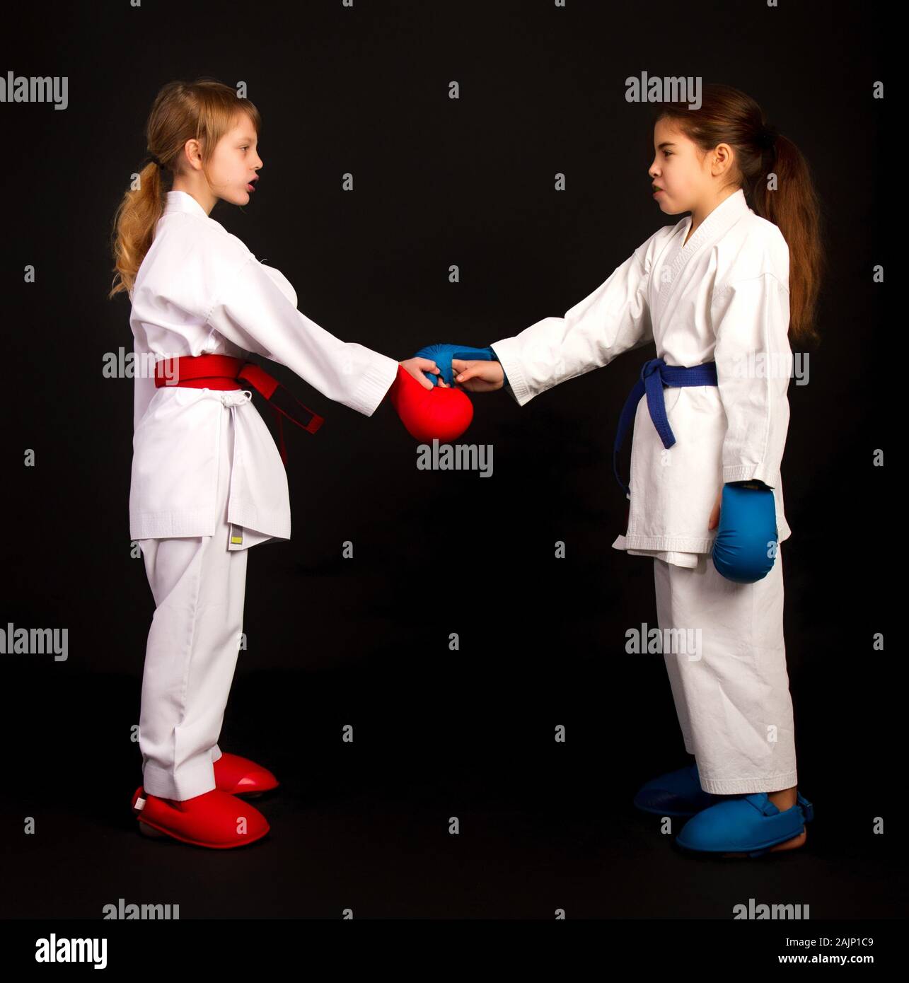 Two little karate women in white kimonos, one in red and the other in