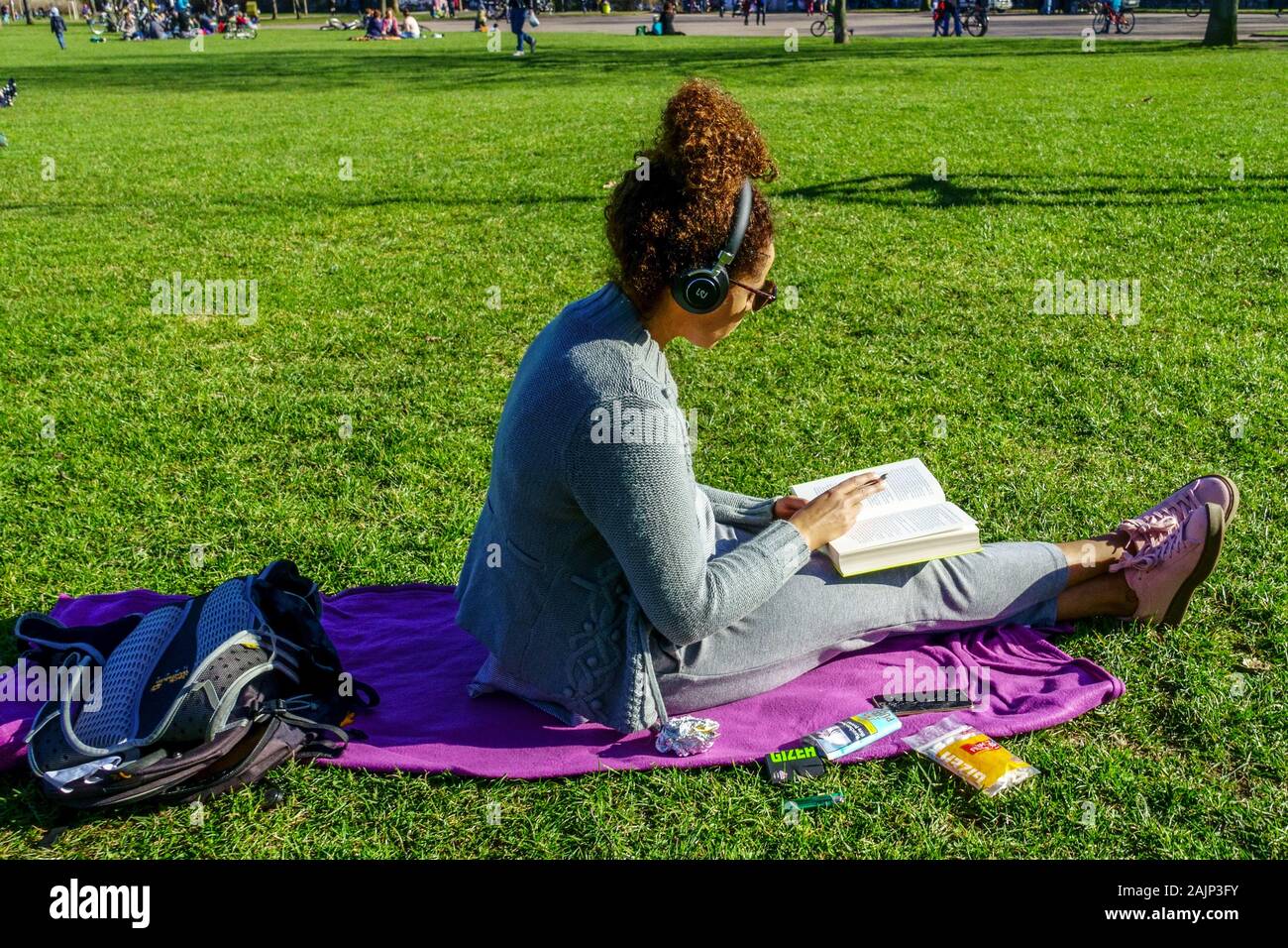 Germany teenager outside a teenage girl with headphones listening to music and reading a book in the park Neustadt Dresden city lifestyle Generation Z Stock Photo