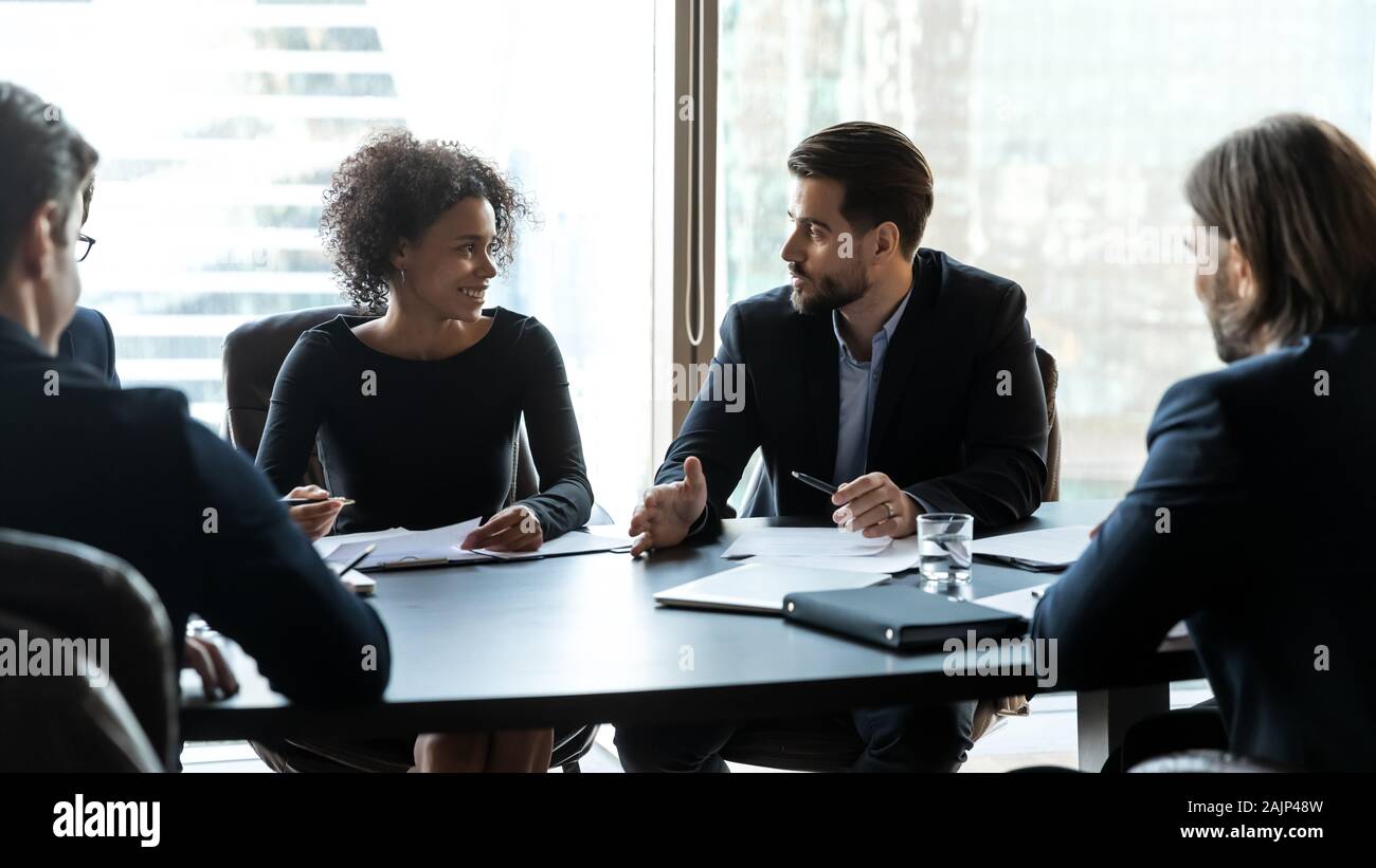 Multiracial businesspeople brainstorm discuss document at briefing Stock Photo