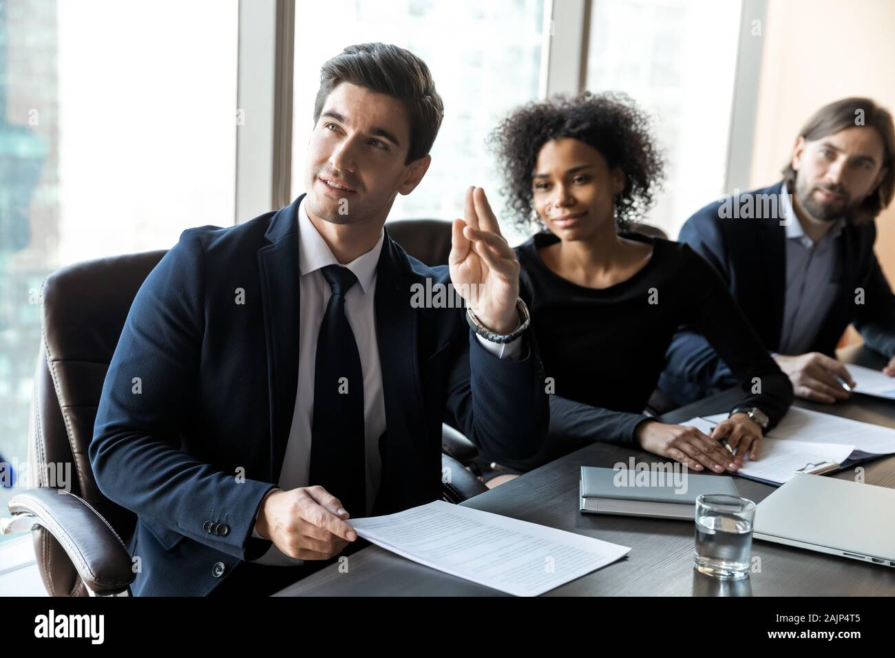 Motivated male employee raise hand participate in team discussion Stock Photo