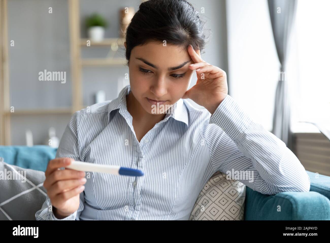 Worried young infertile indian woman holding pregnancy test Stock Photo