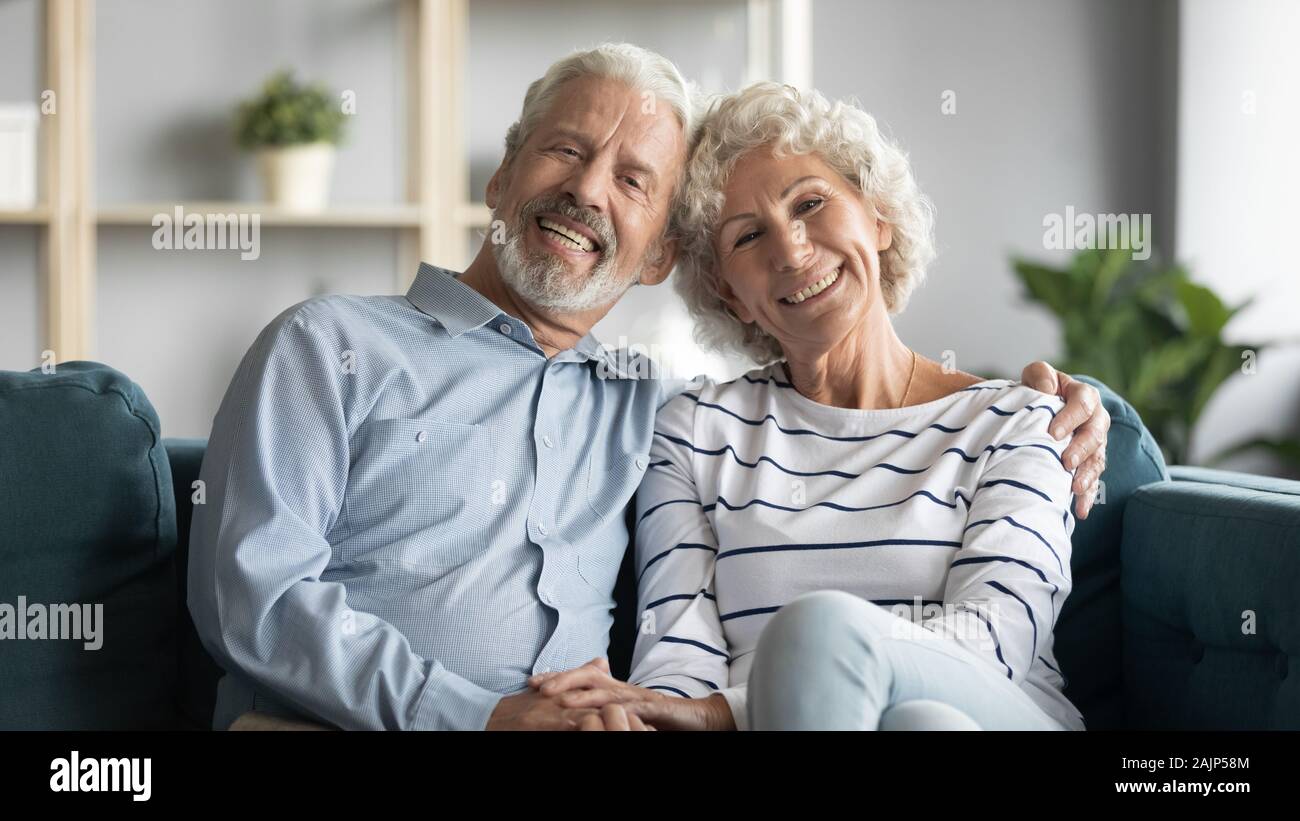 60s loving couple sitting in living room posing looking at camera Stock Photo