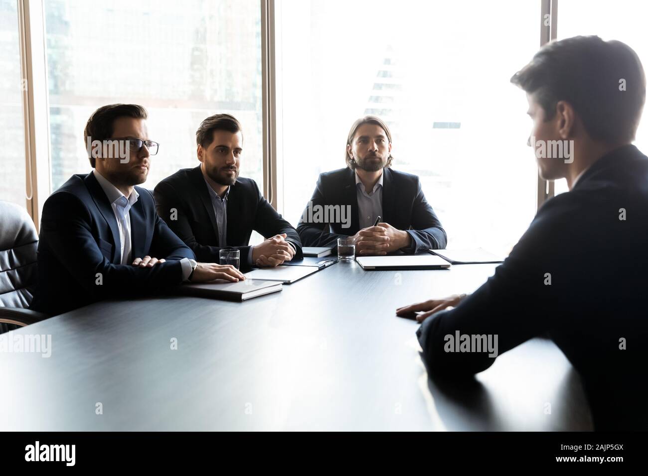 Male candidate speak with serious employers at meeting Stock Photo