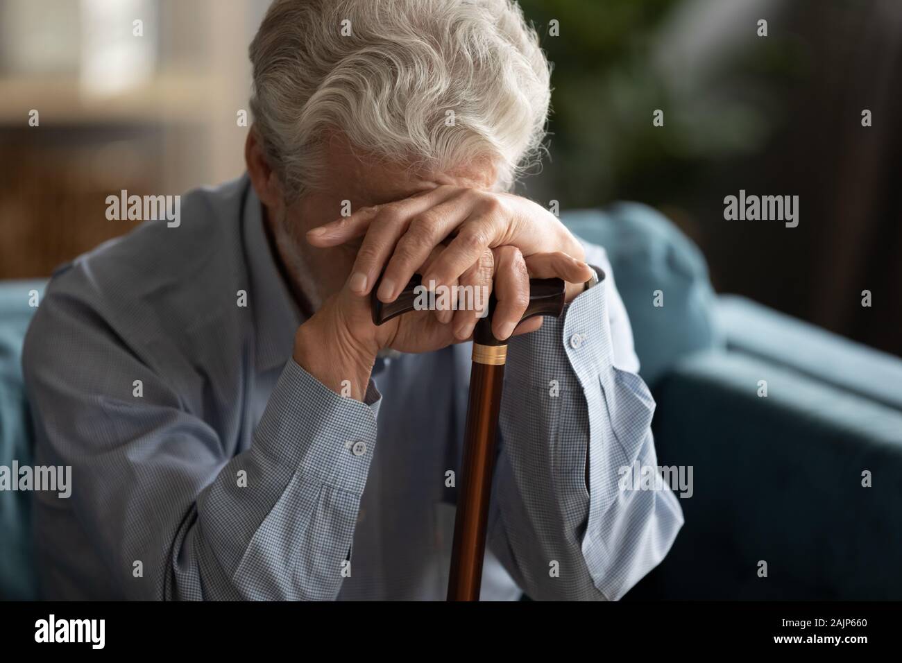 Sad elderly man covering his face with hand holding cane Stock Photo ...