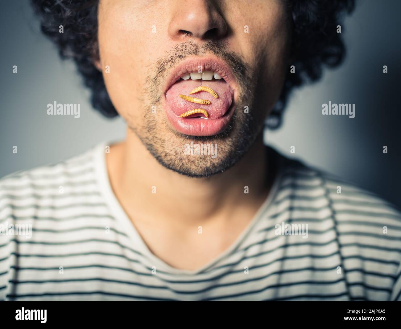 Studio Shot Of A Young Man With Edible Worms On His Tongue Stock Photo Alamy