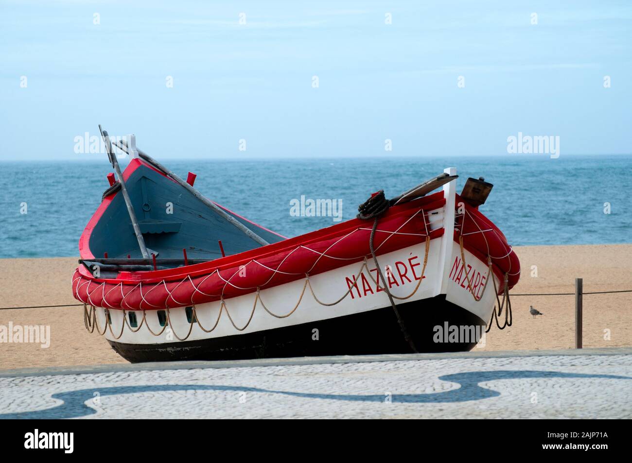 Traditional red, white and blue wooden Portuguese fishing boat on the beach of Nazare, Portugal. These boats are on display by the Dry Fish Museum Stock Photo