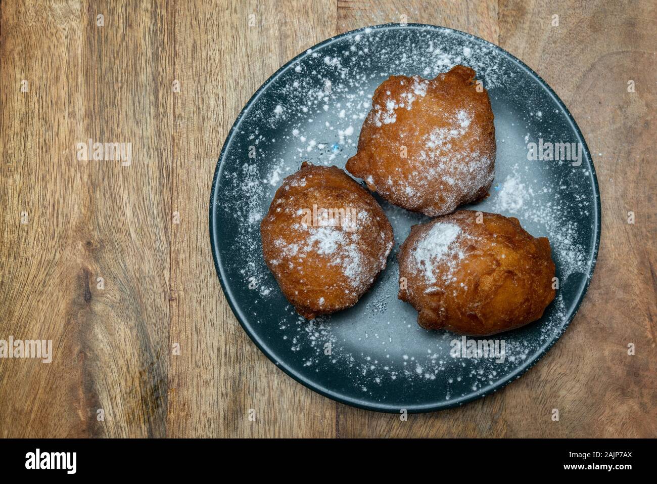 Traditional Dutch doughnut on a plate, with powder sugar on it. Called oliebollen in the Netherlands. Mostly eaten on New Year's Eve. Stock Photo