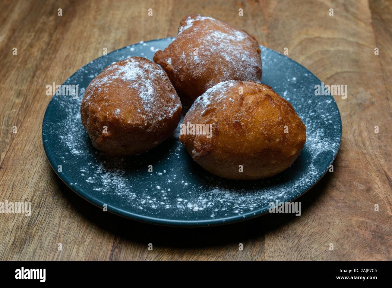 Traditional Dutch doughnut on a plate, with powder sugar on it. Called oliebollen in the Netherlands. Mostly eaten on New Year's Eve Stock Photo