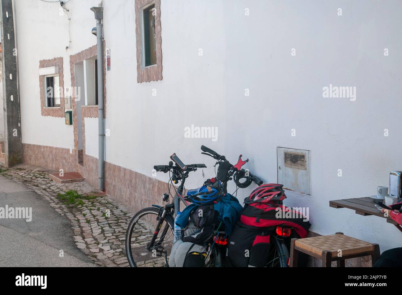 Bicycle tourists at rest at a small cafe in a Quaint blue and white houses line a street in a small town in the municipality of Obidos, Portugal Stock Photo