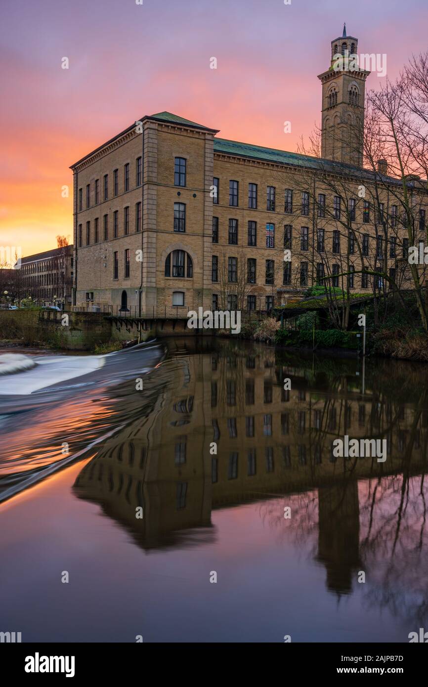 New Mill at the Salts Mill UNESCO Heritage site in Saltaire, Yorkshire, is highlighted by a fiery sunrise on a winter morning. Stock Photo