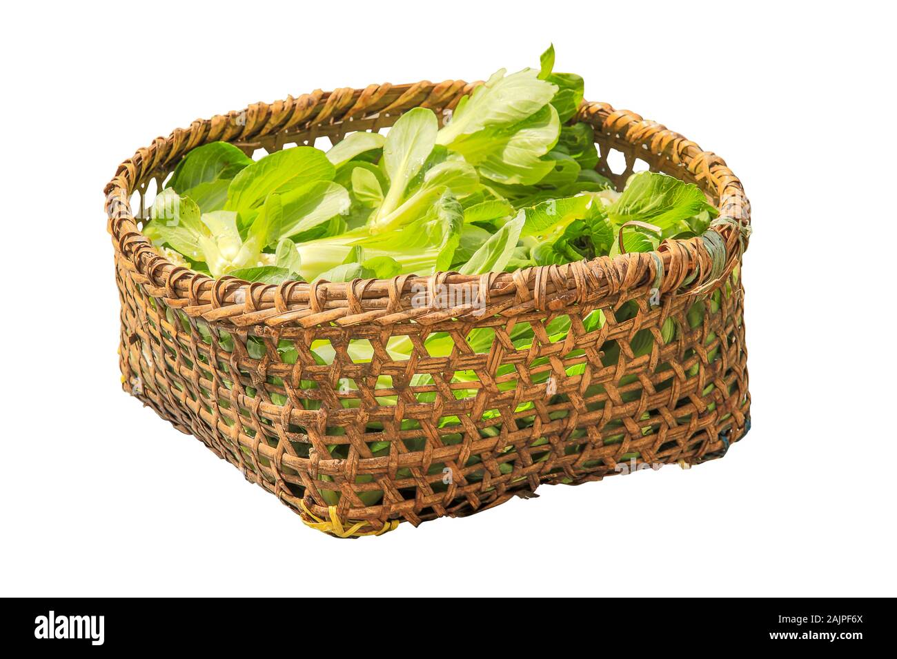 Fresh salad in a wicker basket on a white background. Stock Photo