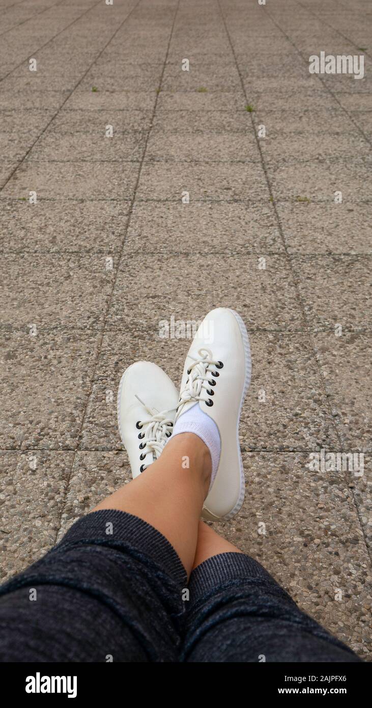 Women feet wearing white fashion sneaker shoes in hipster style. Negative  space. Copy space for text Stock Photo - Alamy