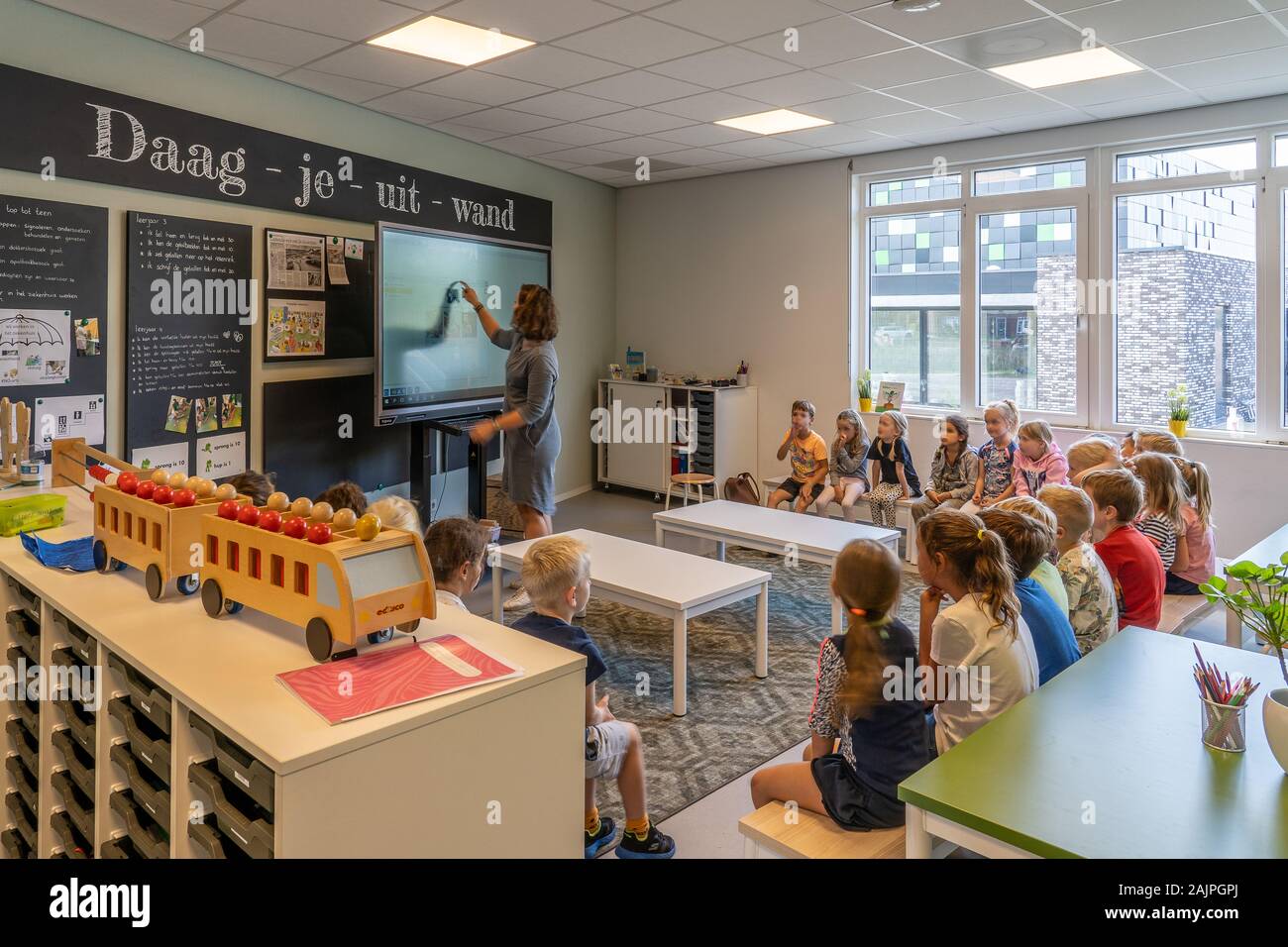 NIJMEGEN / NETHERLANDS-SEPTEMBER 13, 2019: Children sitting in a classroom listening to the teacher. Teacher is writing on a blakboard Stock Photo