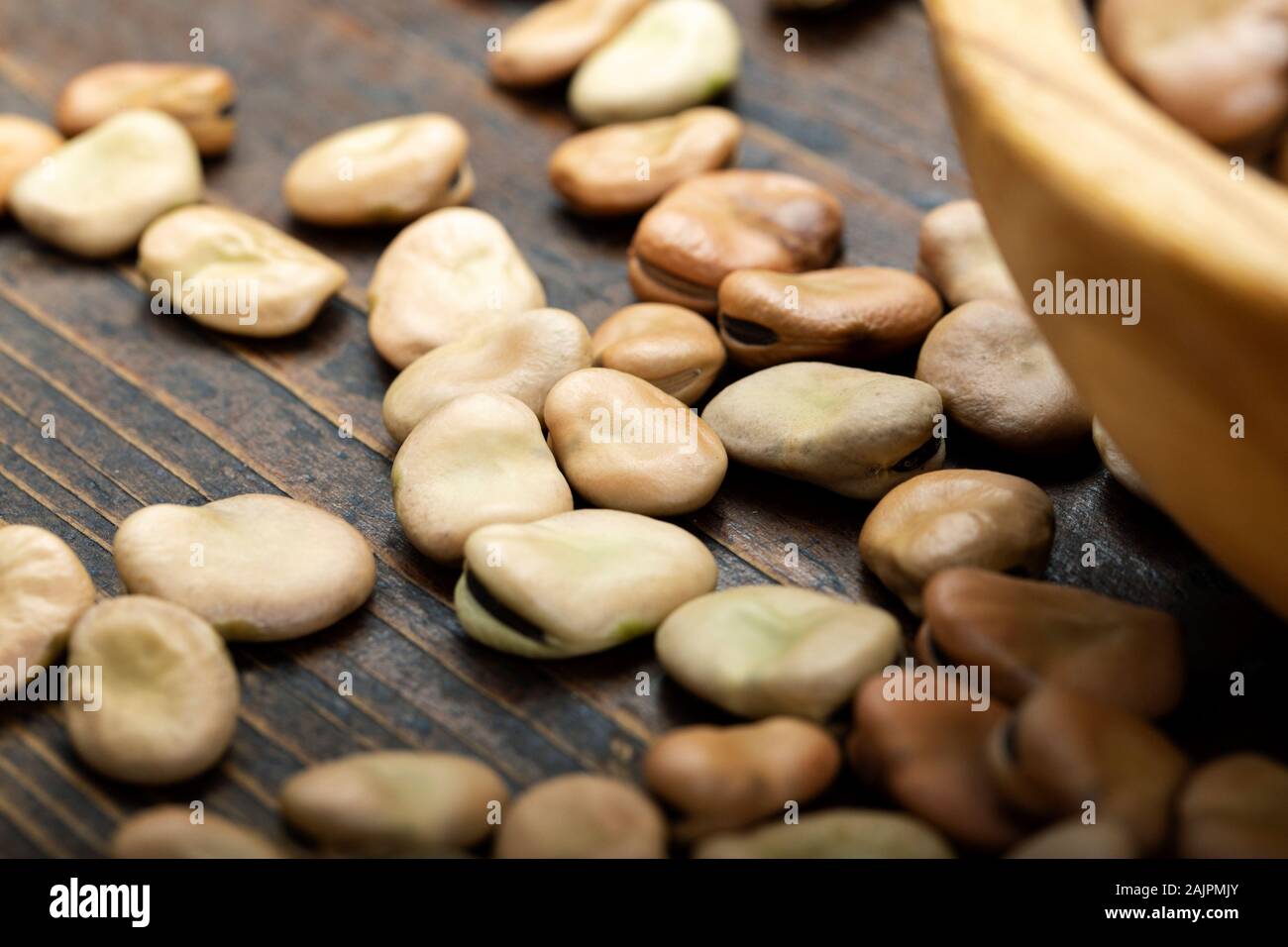 dry broad beans sprinkled on a brown wooden background. place for text. clearly visible bean texture Stock Photo